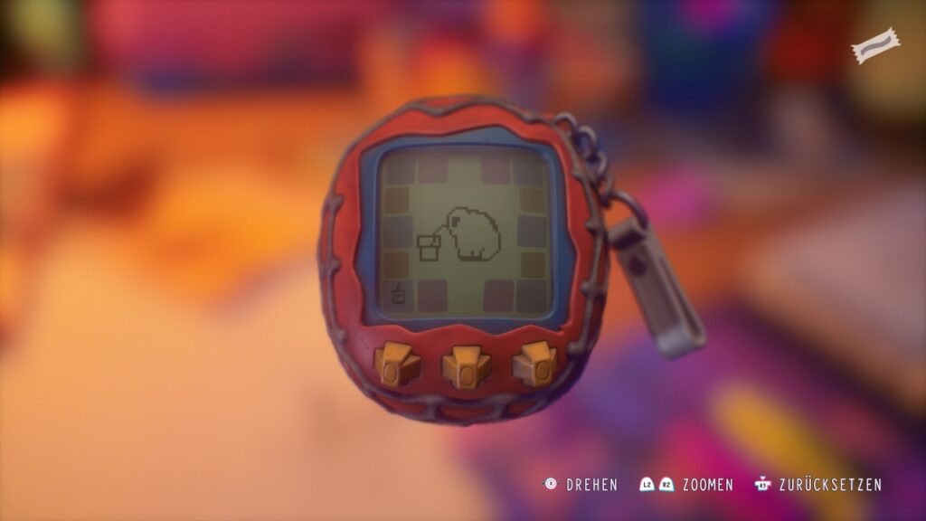 Aufgehobenes elektronisches Haustier, das wie ein rundliches Tamagotchi mit schwarzweißem Bildschirm aussieht. Das kleine Tier trinkt gerade.