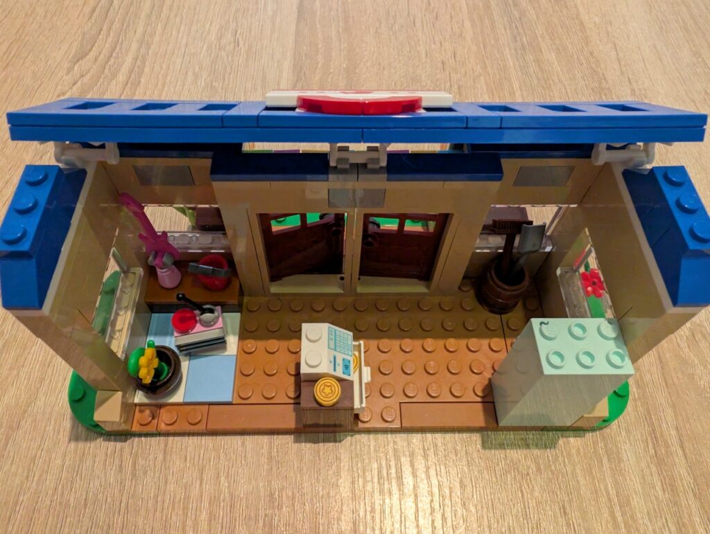 Foto vom Inneren von Nooks Laden, Blick von oben. Links Produkte, in der Mitte Kasse, rechts ein Schrank.