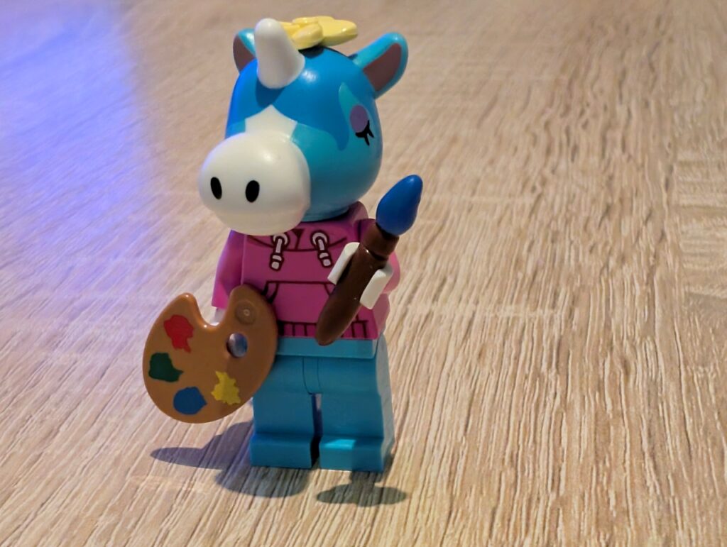Jimmy einzeln stehend mit Palette und Pinsel in den Händen, auf dem Kopf eine gelbe Blüte.