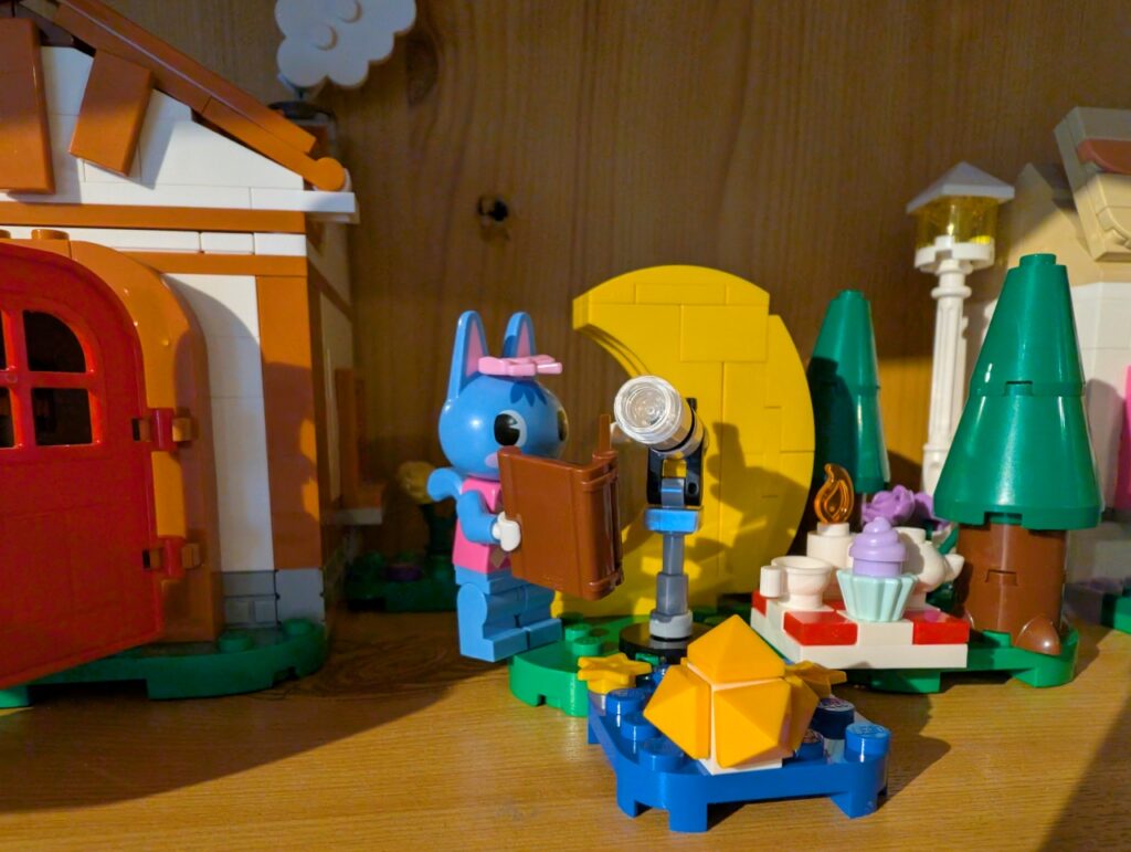 Nahaufnahme von Teleskop und Sophie. Hier steht ein kleines Picknick. Im Vordergrund ein kleiner Sternensplitter.