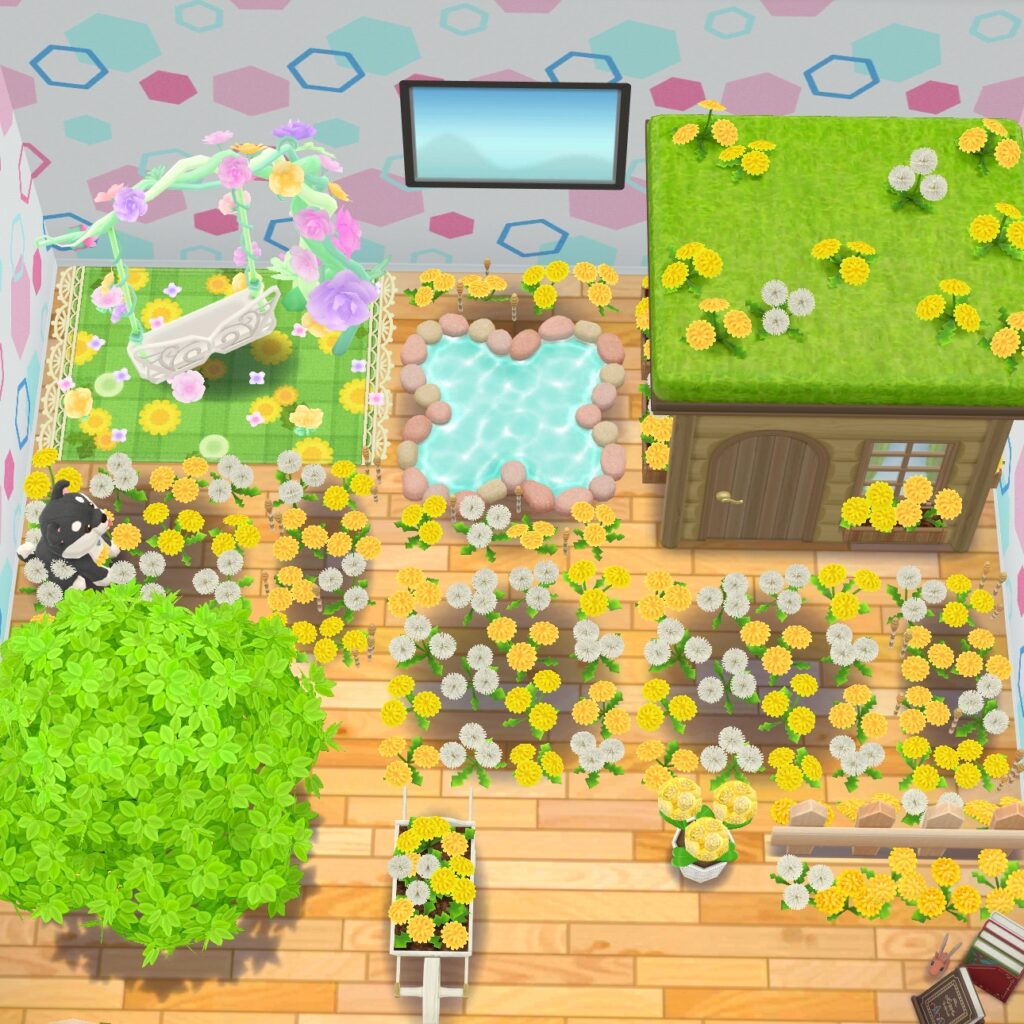 Blick von oben auf den hinteren Bereich des Zimmers. Links ein grüner Teppich mit Löwenzahnmotiv, darauf eine Blumenschaufel. Rechts davon ein Blumenförmiger Teich, daneben eine kleine Hütte mit Löwenzahn auf dem Dach. Davor liegen verschiedene Felder Löwenzahn. Unten Links ist ein Baum, hinter dem ein Plüschhund sitzt. Rechts davon eine Schubkarre mit Löwenzahn. Nach einer Lücke folgen ein Blumentopf mit Löwenzahn und ein kurzer Holzzaun.