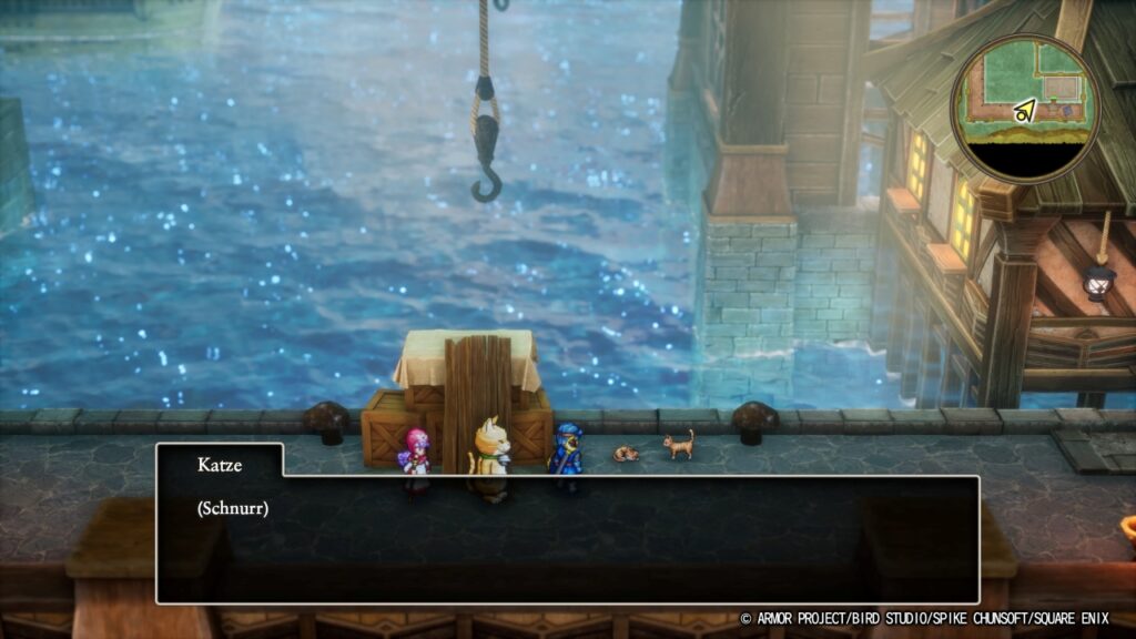 Katze: (Schnurr). Armin trägt ein Katzenkostüm, im Hintergrund glitzert Wasser. Eine Katze liegt eingerollt da, daneben steht eine weitere.