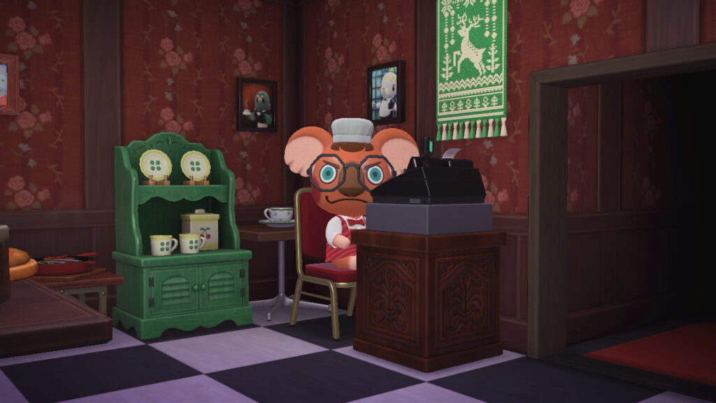 Caroline an der Kasse ihres Internationalen Restaurants mit starrem Blick in die Kamera, gefurchten Augenbrauen und Lächeln.