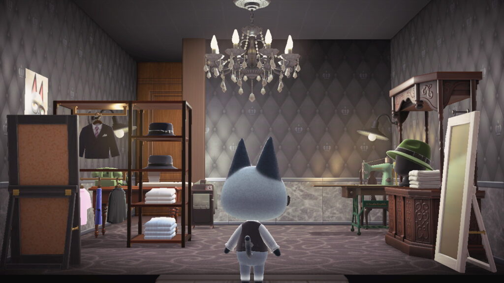 Blick vom Eingang in die Schneiderei. Regale mit Kleidungsstücken, hinten Trennwand.