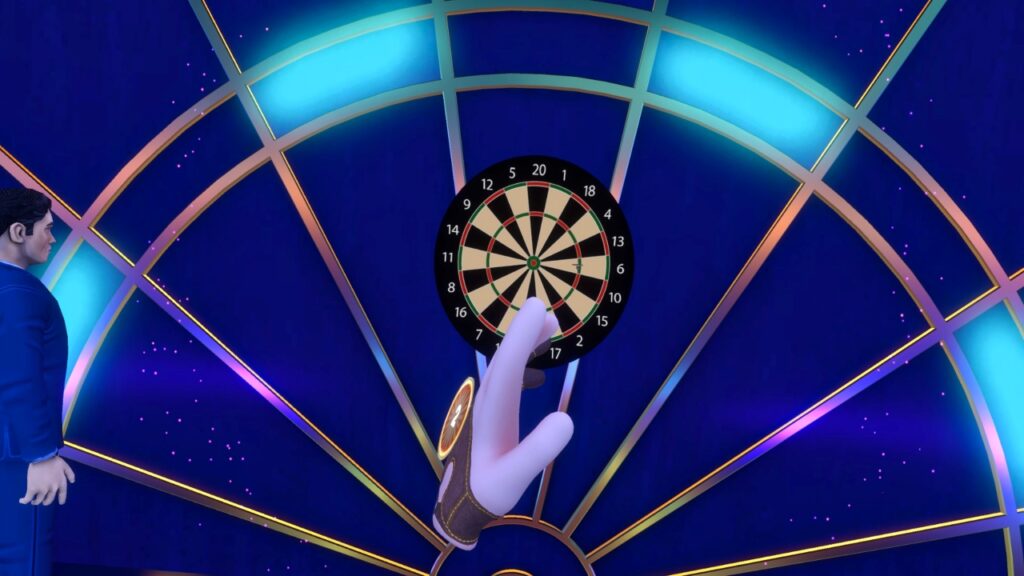 Hand zentriert im Bild, dahinter die Dartscheibe, Pfeil auf Triple-6, links halb der Ansager zu sehen.