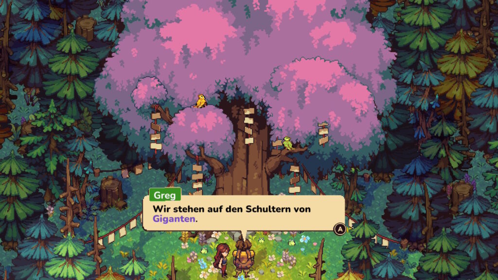 Alessandra und Greg vor dem großen Evertree mit violetten Blättern und an die Äste gehängten Schildern. Greg: "Wir stehen auf den Schultern von Giganten."